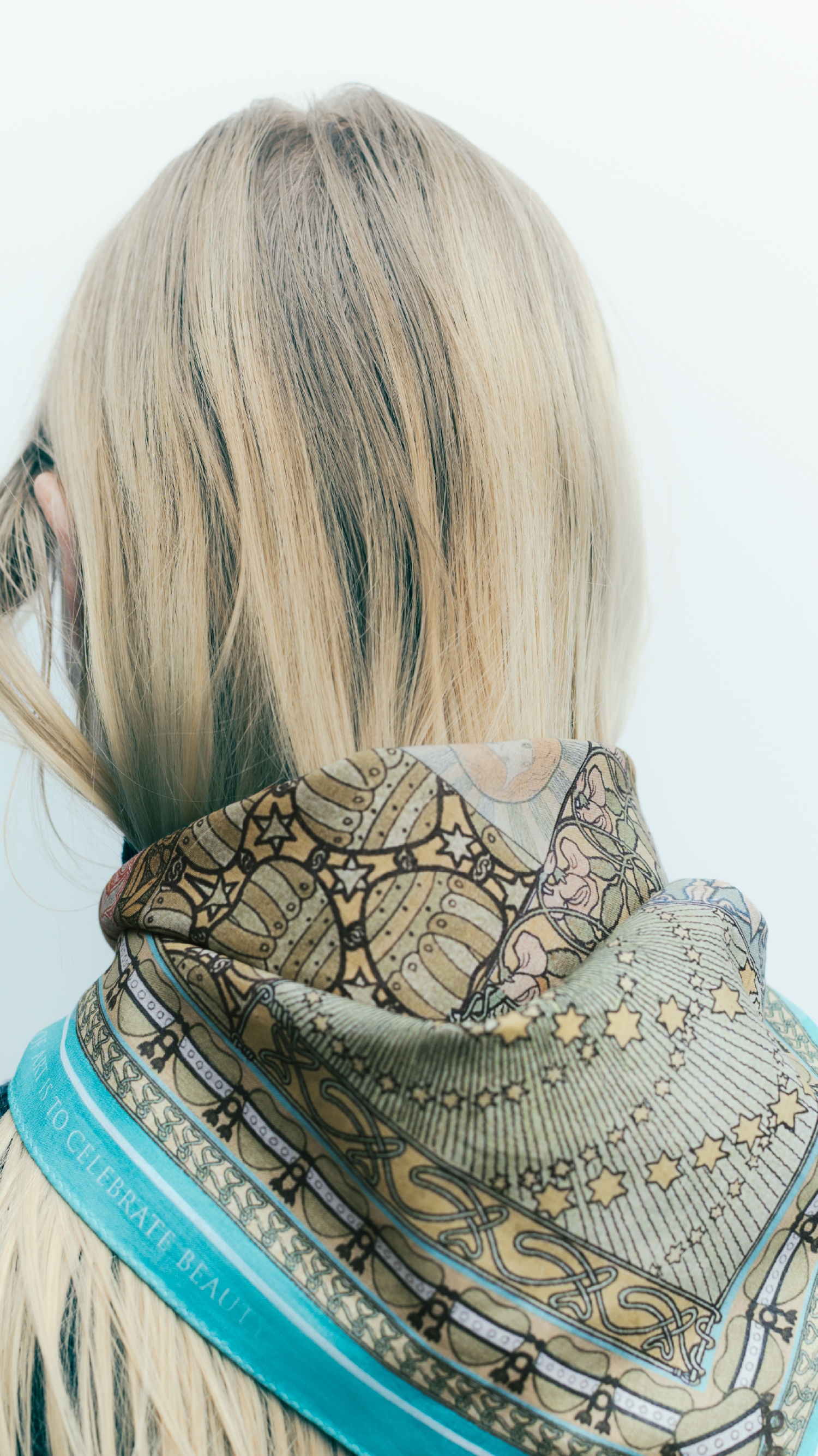 アートハンカチをスカーフの様に結んだ女性の後ろ姿の写真