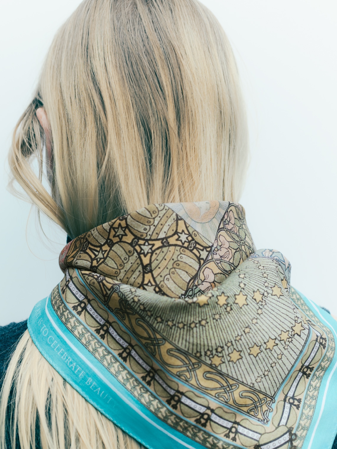 アートハンカチをスカーフの様に結んだ女性の後ろ姿の写真